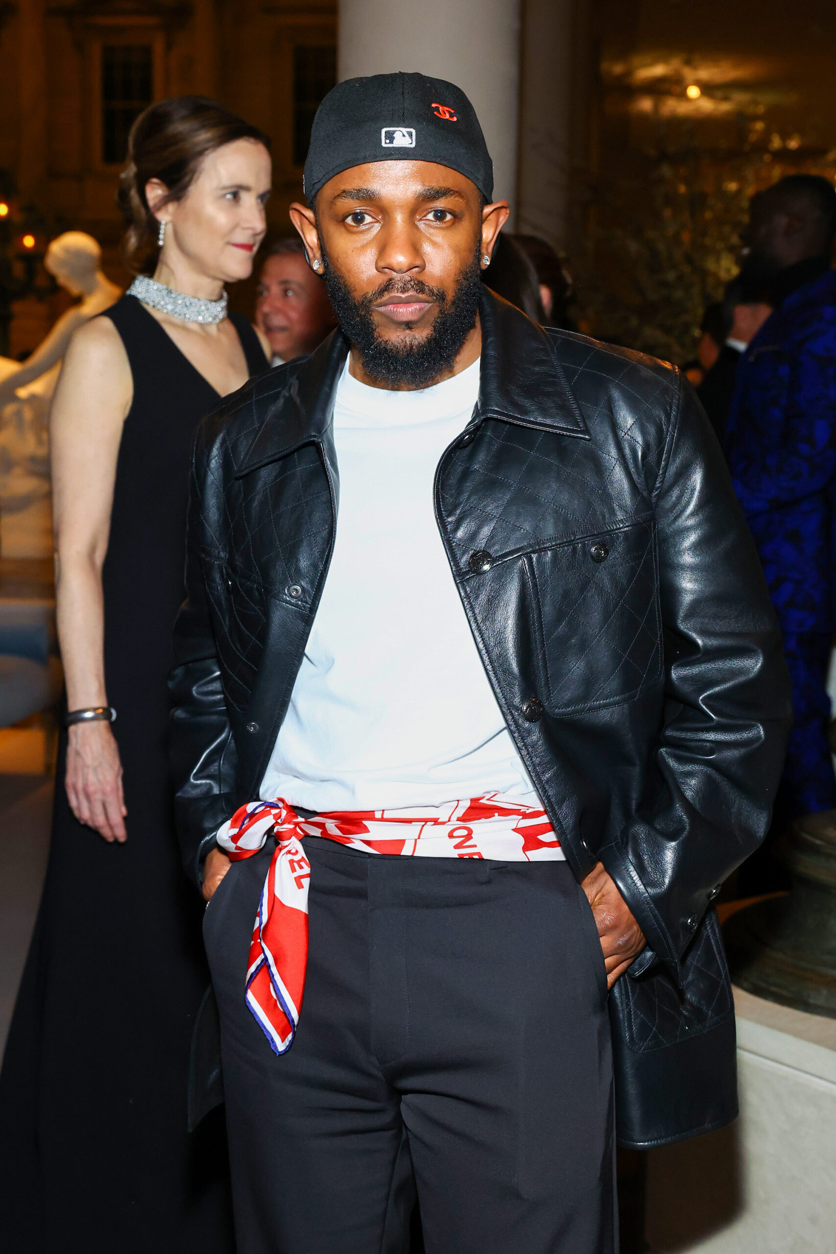 Kendrick LAMAR, American singer, wore a custom black leather jacket inspired by look with CHANEL black wool pants. CHANEL silk scarf, glasses and shoes.
