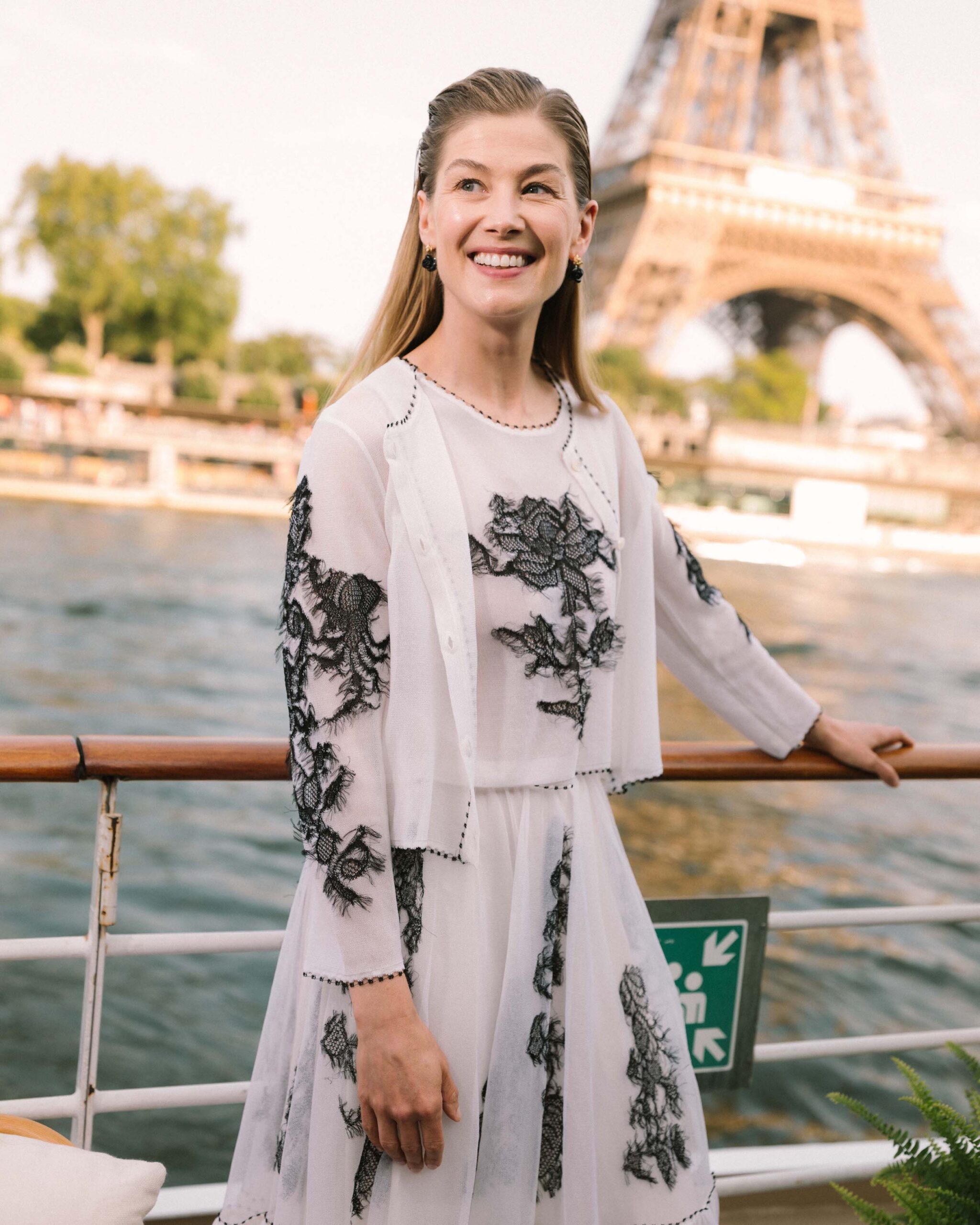 Rosamund Pike in Dior Cruise 2023 Rosamund Pike exuded ethereal charm in a white embroidered silk cardigan, top, and skirt from the Dior Cruise 2023 collection.