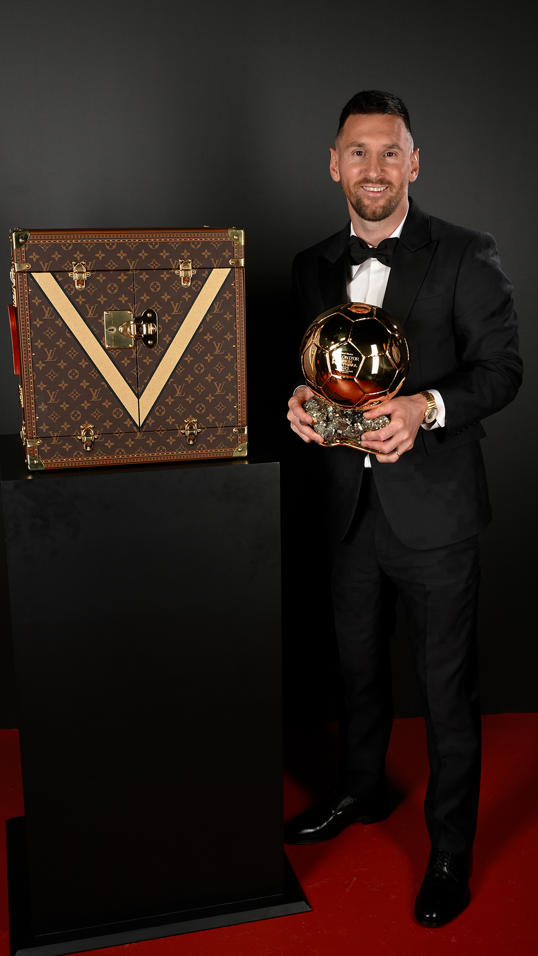 Lionel Messi with the prestigious award, juxtaposed by the iconic Louis Vuitton case.
