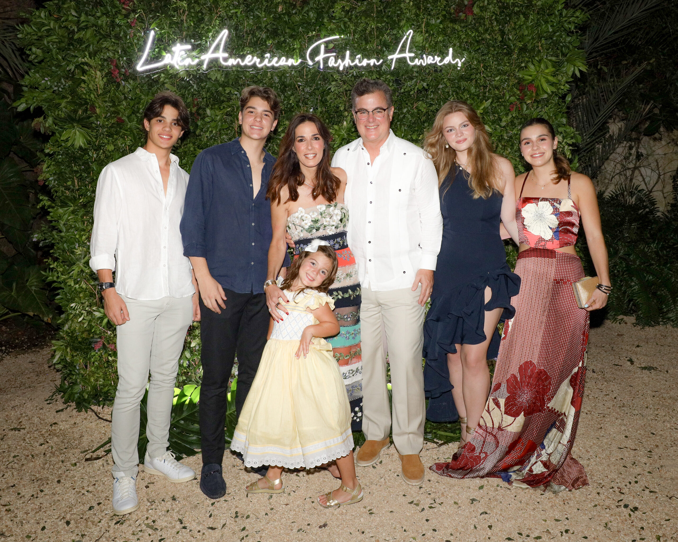&quot;A moment of radiance: Silvia Argüello, surrounded by her family, captures the joy and familial bonds at the Latin American Fashion Awards, set against an oasis of greenery.&quot;