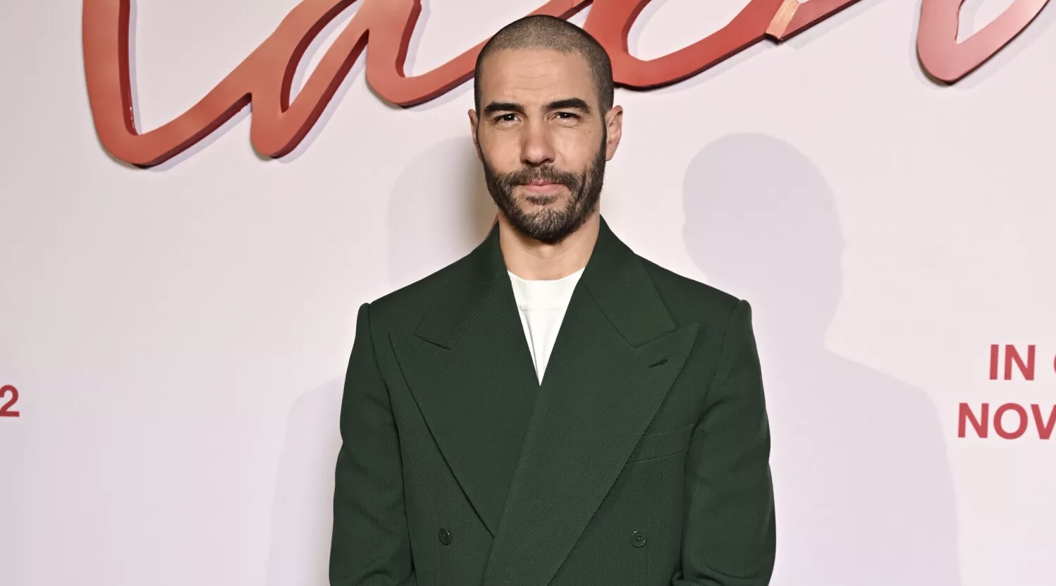 Tahar Rahim stands with effortless grace in a custom green wool suit by Pharrell for Louis Vuitton, paired with a Tambour watch and burgundy loafers, exuding a blend of classic elegance and contemporary fashion sensibility.