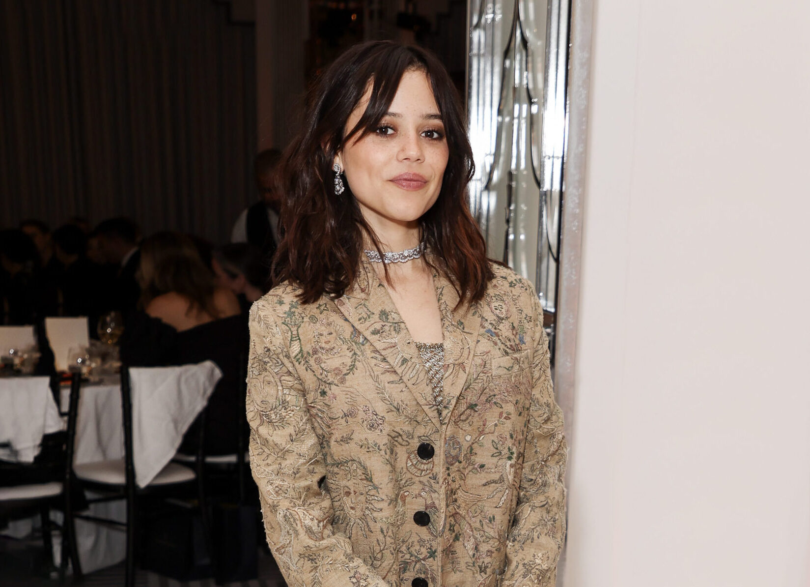 Jenna Ortega arrives at the Harper's Bazaar Women Of The Year Awards in a patterned jacket and sparkling jewelry.