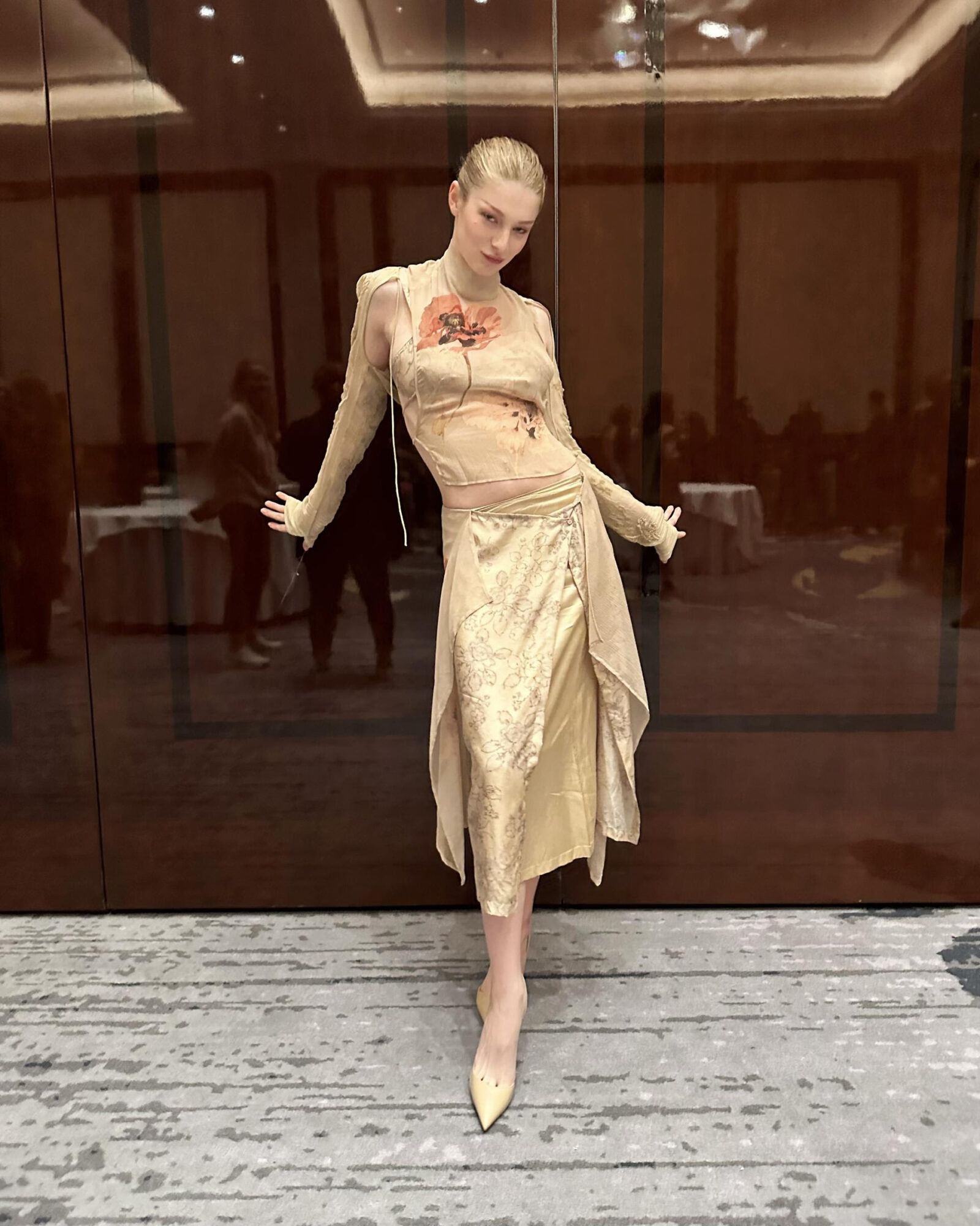 Hunter Schafer captivates in a Dries Van Noten ensemble, featuring a sheer floral-embroidered top and a lustrous gold asymmetrical skirt, at &quot;The Ballad of Songbirds &amp; Snakes&quot; event in Berlin – a harmonious blend of avant-garde fashion and classic elegance.