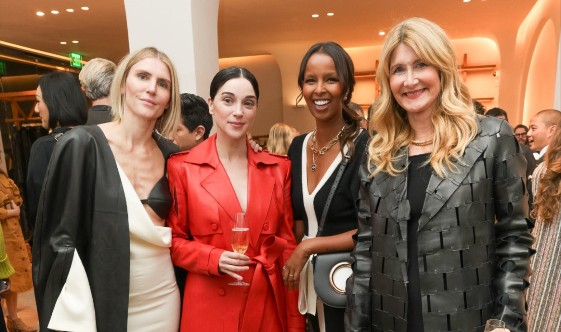 At a prestigious event, Gabriela Hearst, St. Vincent in red, Roda Ahmed with a beaming smile, and Laura Dern in a textured jacket, showcase a blend of individual style and the sustainable luxury of Gabriela Hearst's brand.