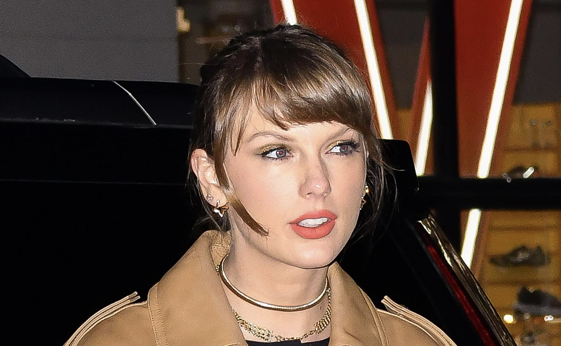 Taylor Swift in Manhattan wearing a classic trench coat paired with Louis Vuitton Blossom Fine Jewelry, exuding luxurious style in a metropolitan setting.