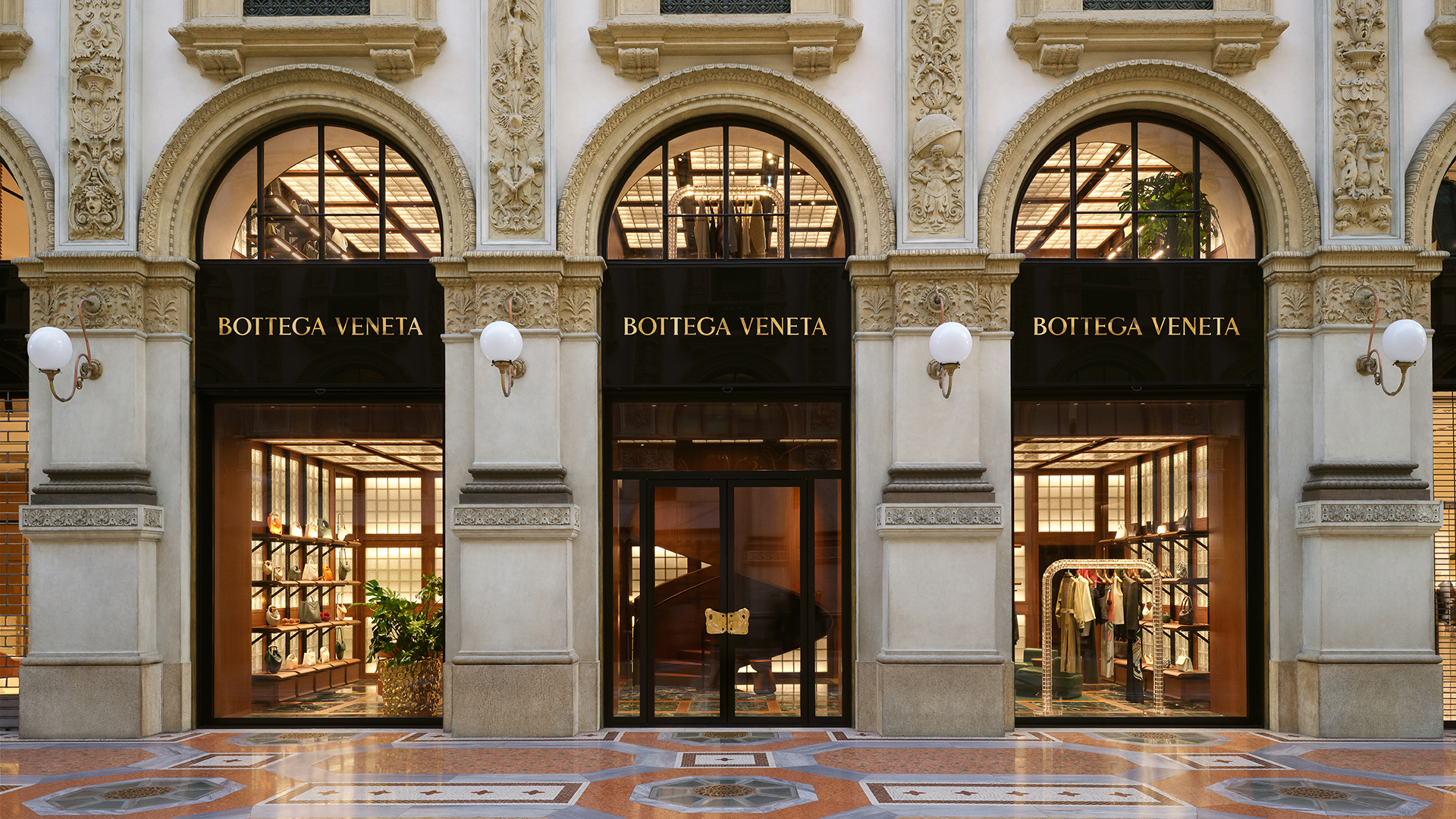 The façade of Bottega Veneta's boutique in the ornate Galleria Vittorio Emanuele II, featuring arched windows and intricate architectural details.