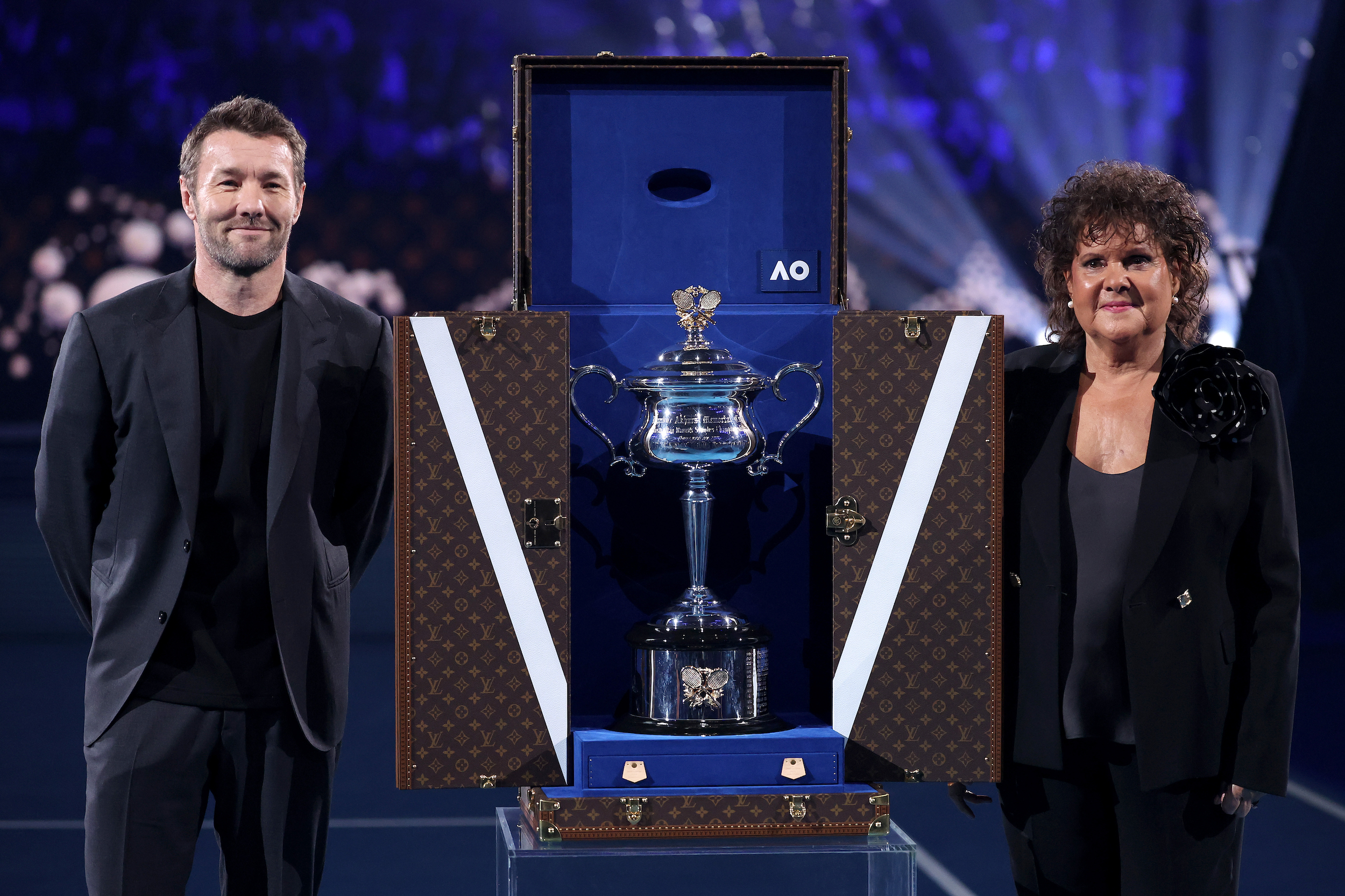 Joel Edgerton and Evonne Goolagong Cawley stand beside the open Louis Vuitton trophy trunk displaying the Daphne Akhurst Memorial Cup at the 2024 Australian Open.