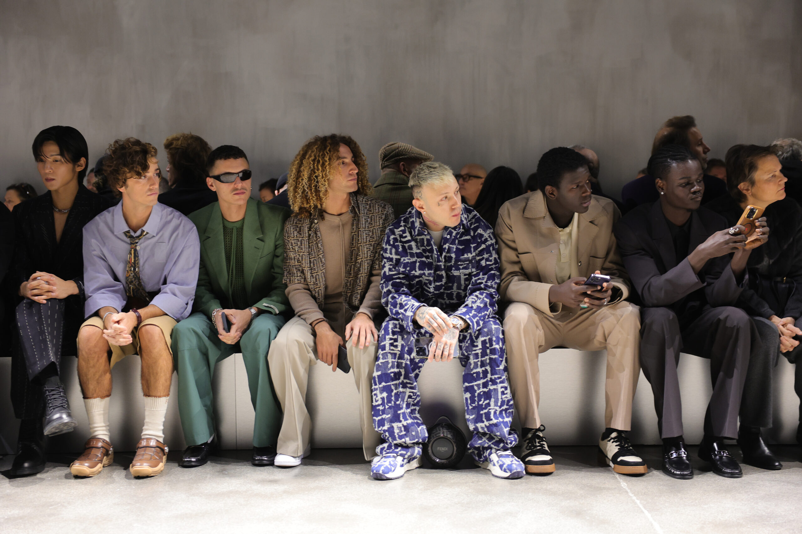 Ren Meguro, Guitarricadelafuente, Arón Piper, Lazza, Seydou Sarr, and Moustapha Fall seated front row at the FENDI Fall/Winter 2024/2025 show, showcasing an eclectic mix of personal styles against the minimalist backdrop of the runway.