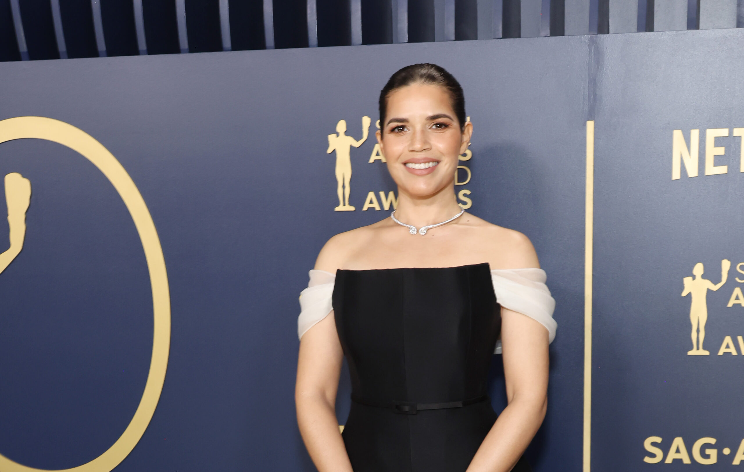 America Ferrera smiling confidently in a black Dior Haute Couture dress at the 30th Annual Screen Actors Guild Awards.
