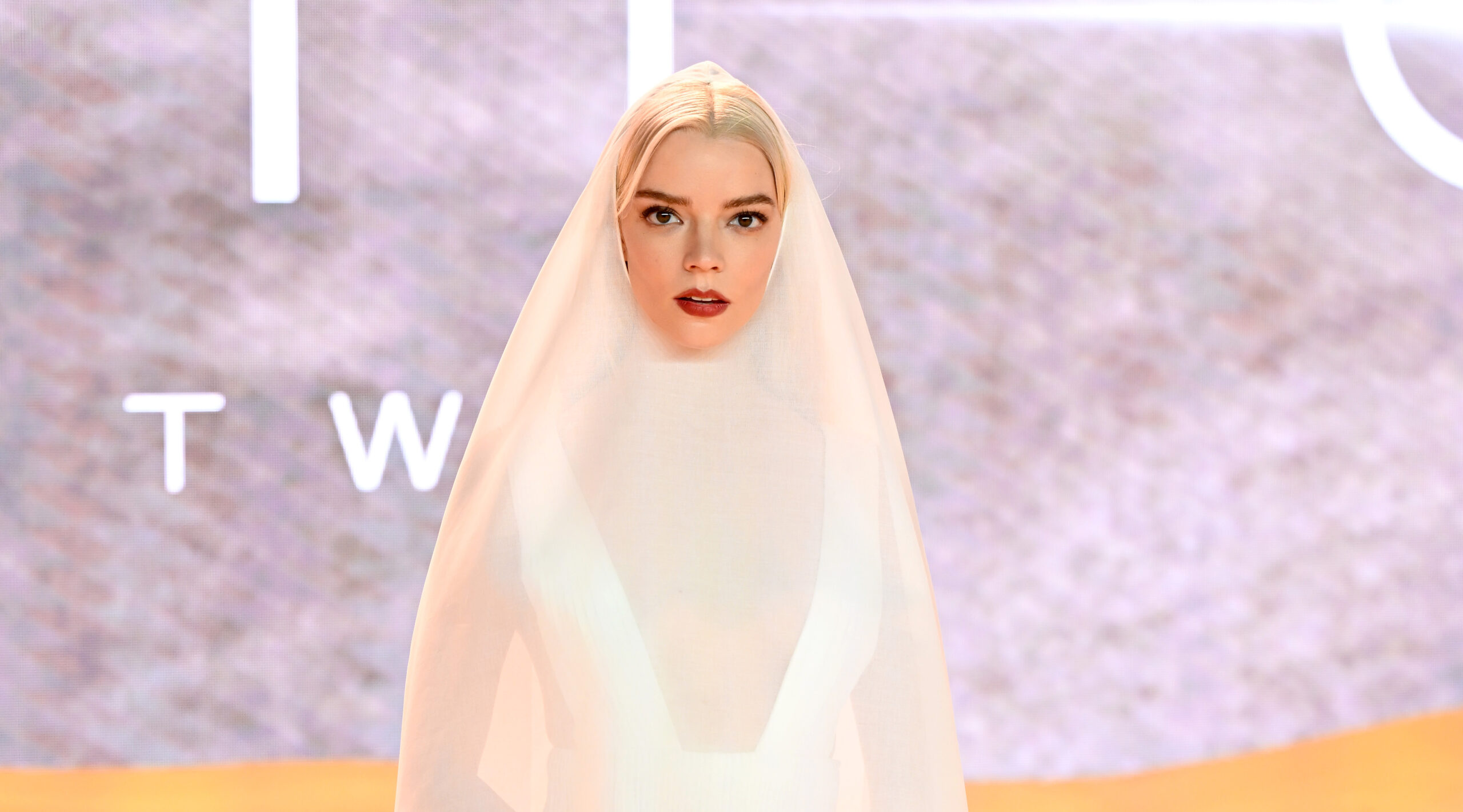 Anya Taylor-Joy stands enveloped in a flowing white cotton organdie cape over a silk pleated dress by Dior Haute Couture at the "Dune: Part Two" world premiere in Leicester Square.