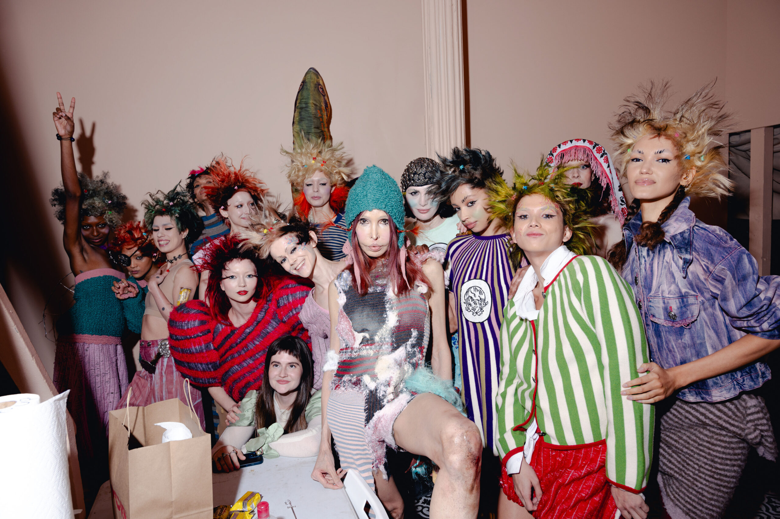 A group of models pose backstage at Pipenco's Ready-to-Wear show, each showcasing a unique, whimsical outfit from the collection that embodies the spirit of playful and chaotic childhood themes.