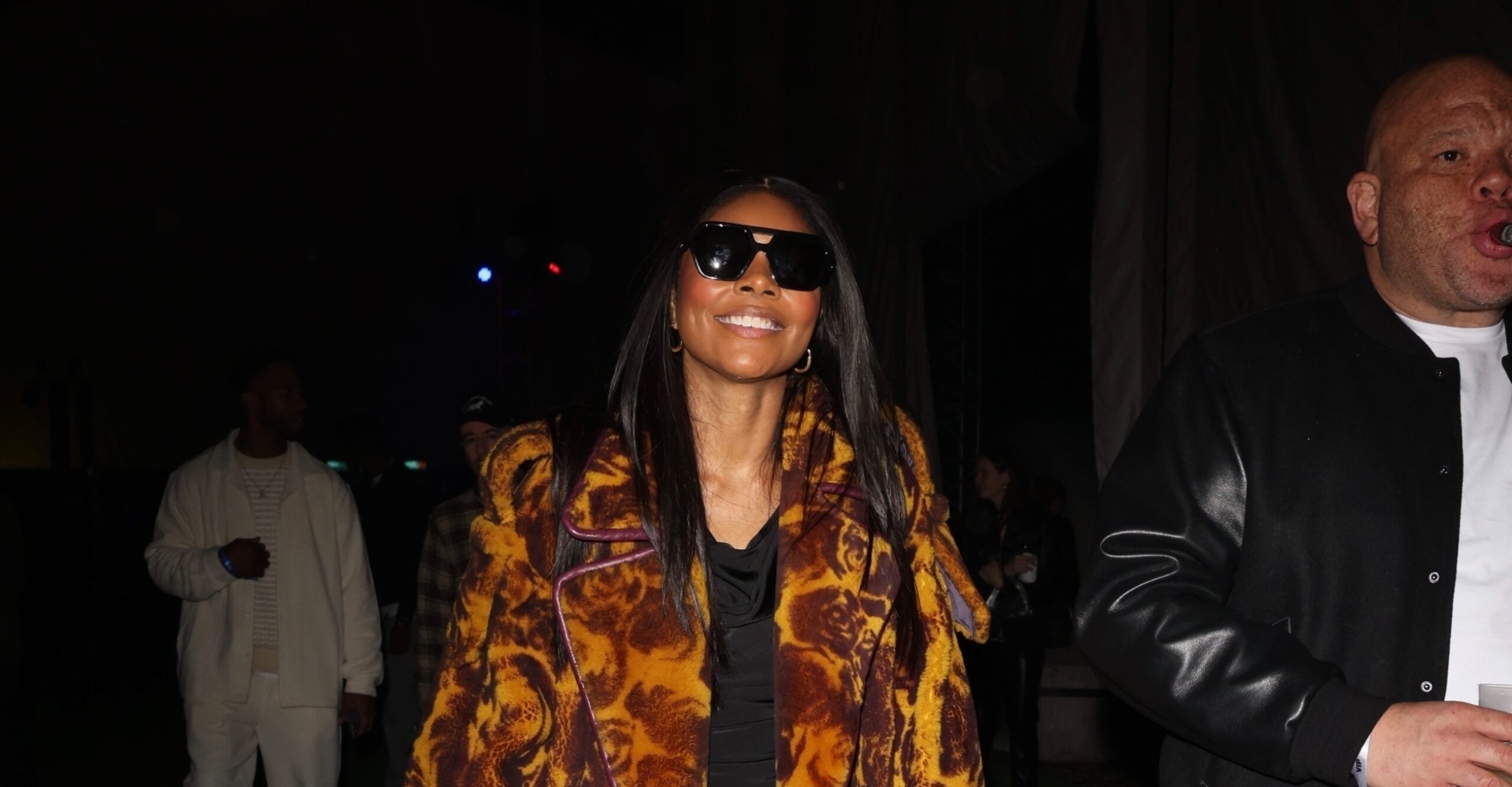 Gabrielle Union smiling in a rose print shearling Burberry trench coat at a pre-Super Bowl party.