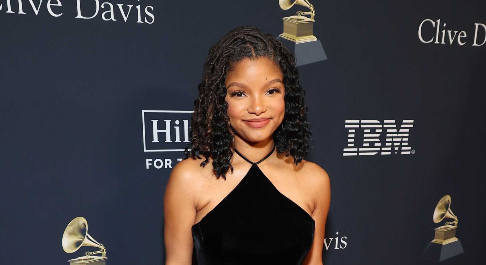 Halle Bailey captures the spotlight at the Pre-Grammy Gala, wearing a stunning black velvet Gucci dress with high splits and silk duchesse straps.
