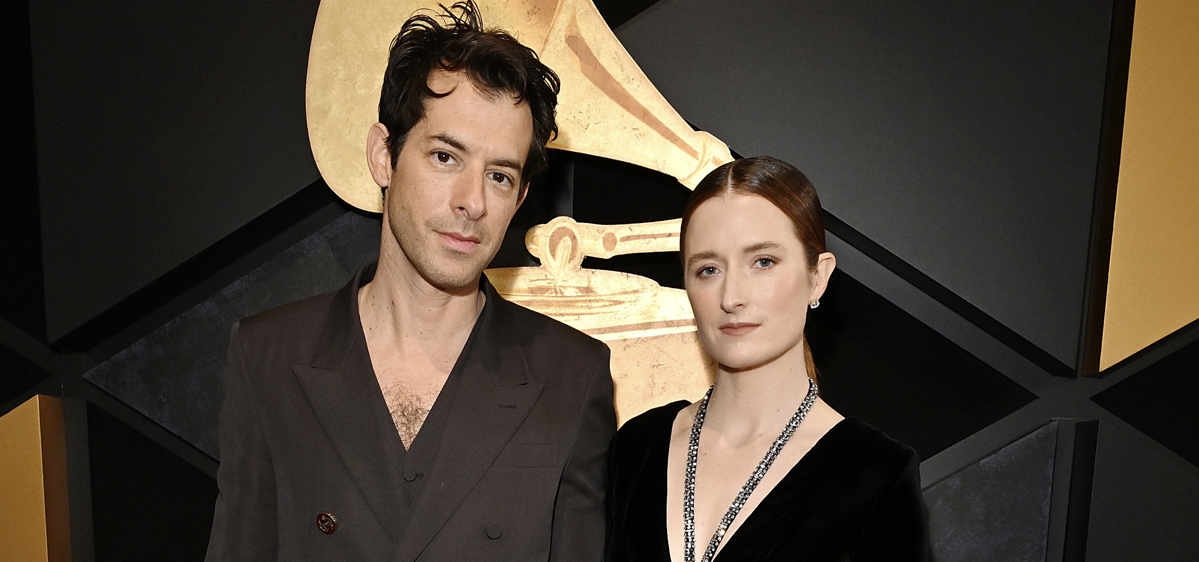 Mark Ronson and Grace Gummer pose together at the 66th GRAMMY Awards, with Mark in a double-breasted, dark suit and Grace in a black velvet dress with a bold cutout and high slit.