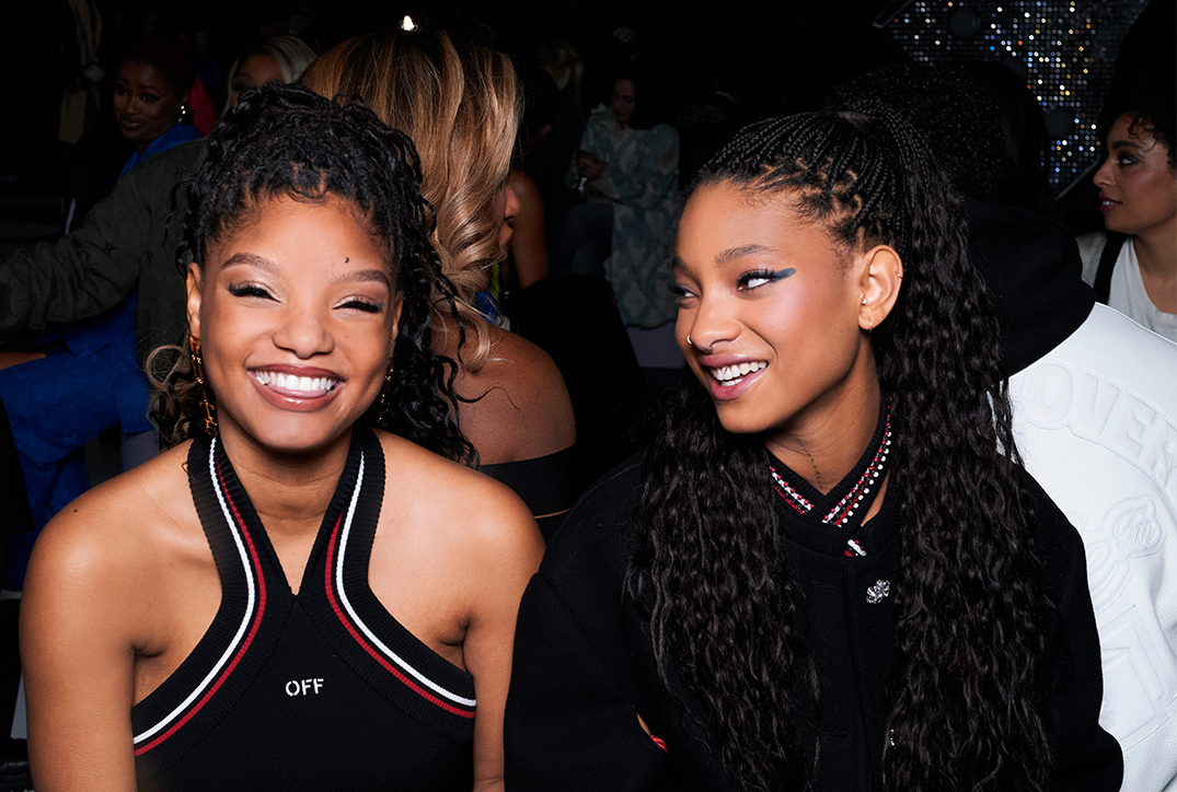 Halle Bailey and Willow Smith are pictured enjoying a lively moment together, with genuine smiles and bright expressions, reflecting the vibrant atmosphere of Paris Fashion Week.