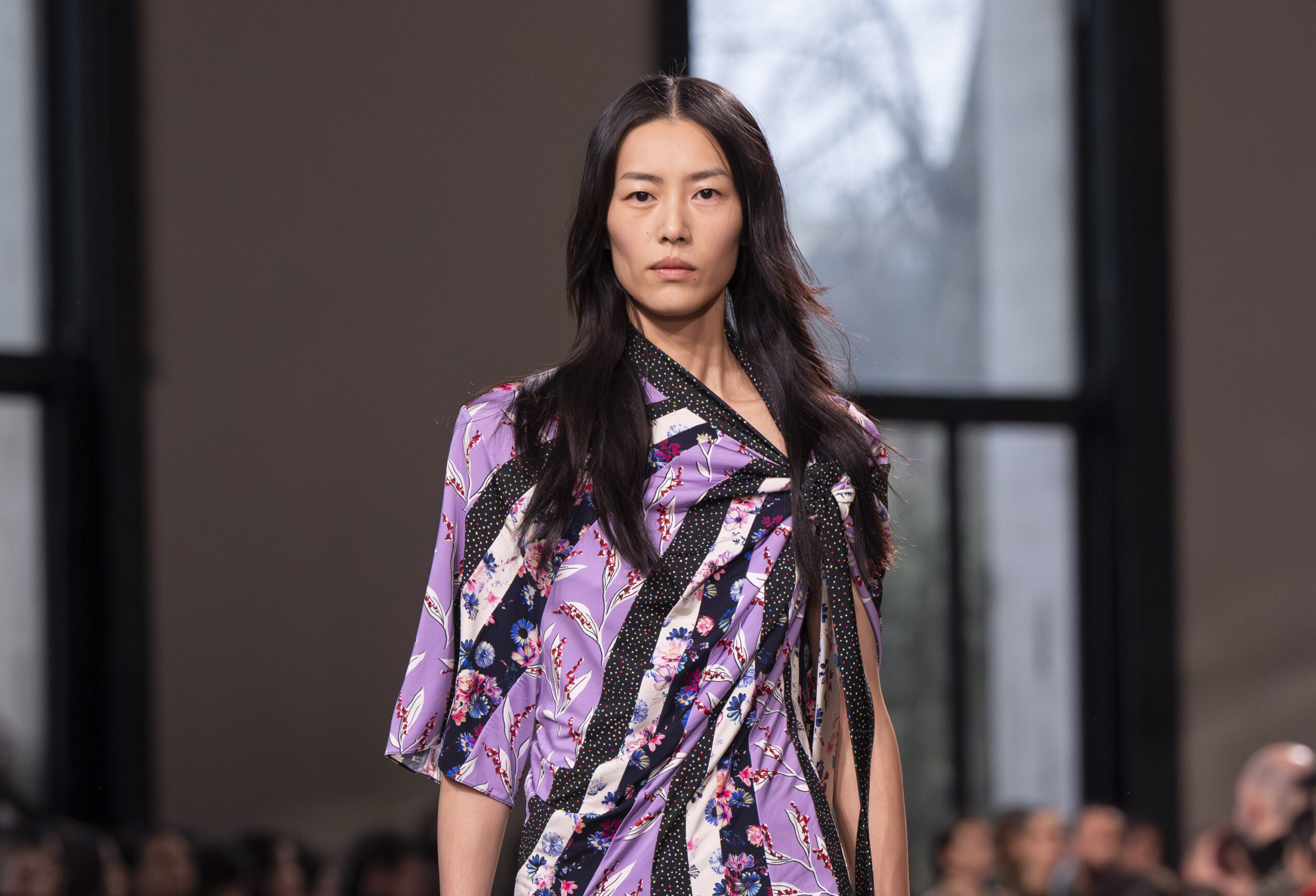 A model dons a purple patterned wrap dress with intricate floral and polka dot designs from Rabanne's Fall/Winter 2024-2025 collection at Paris Fashion Week.