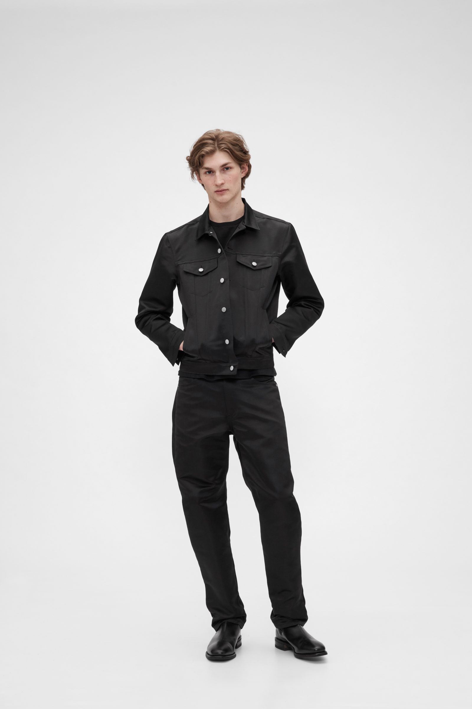 GapStudio Satin Icon Jacket and 90s Loose Pants in sleek black with contrast white buttons, offering a modern interpretation of classic workwear silhouettes. Available for pre-sale March 8, exclusively on Gap.com. $198 for jacket, $128 for pants.